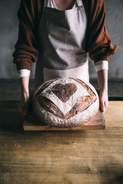 Bakery employee holding a freshly baked loaf of bread.